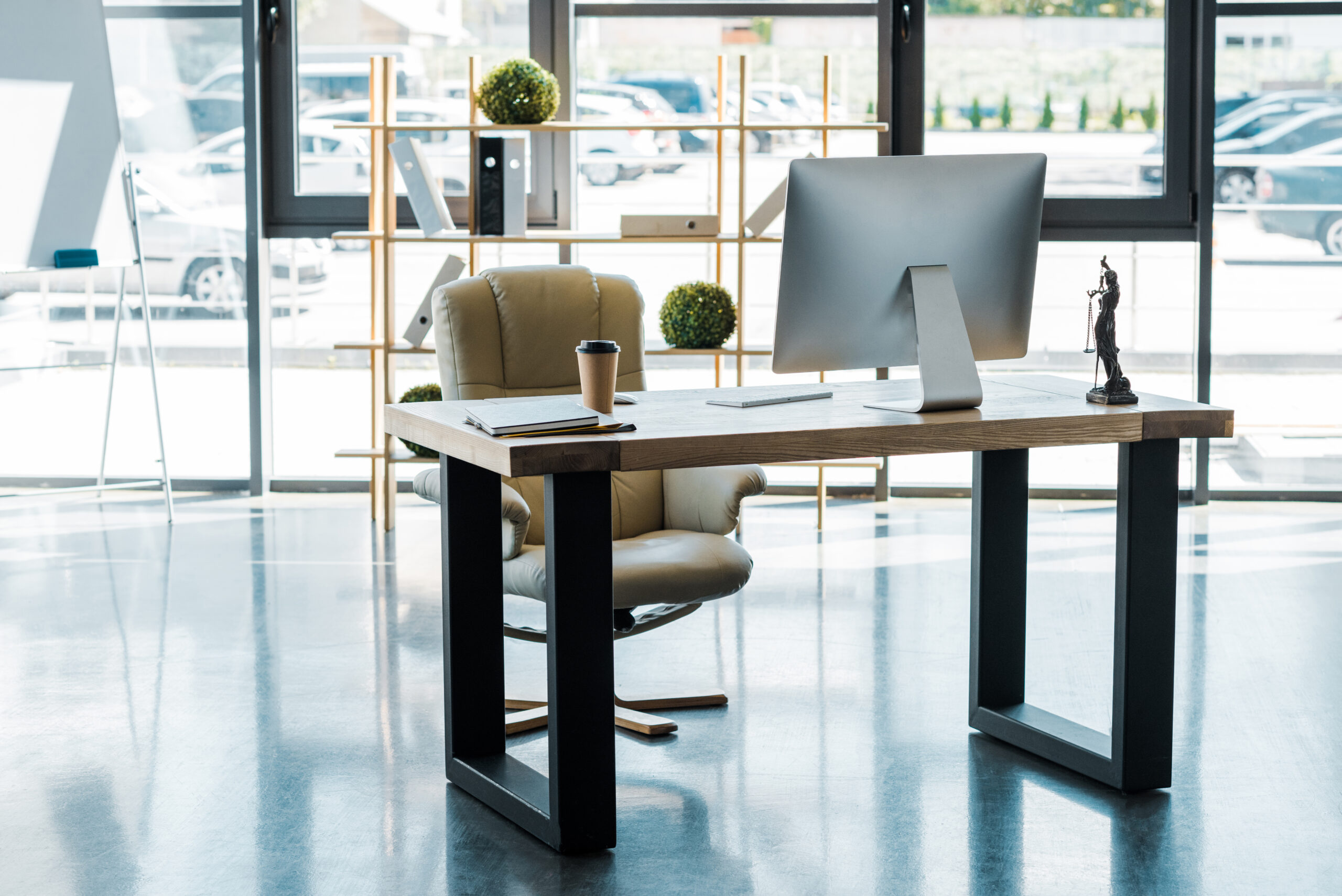 interior of business office with computer, coffee to go and themis statue on table